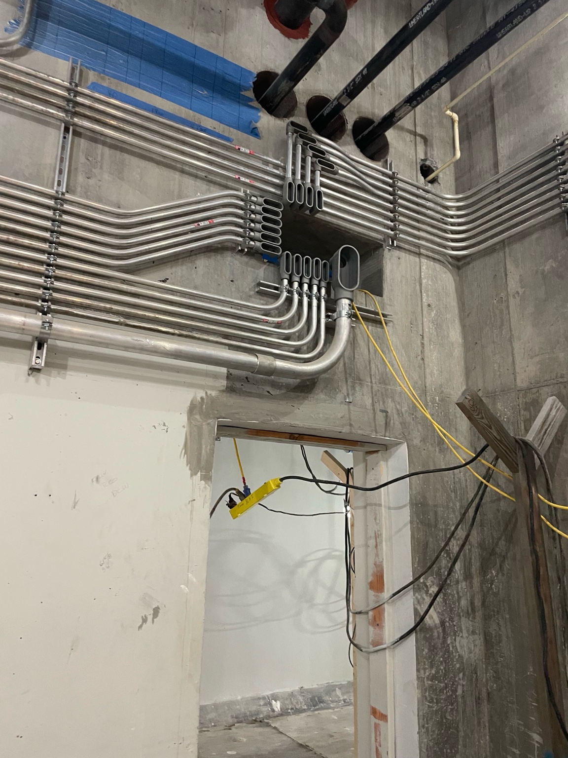 Industrial conduits routed across a concrete wall and through a doorway